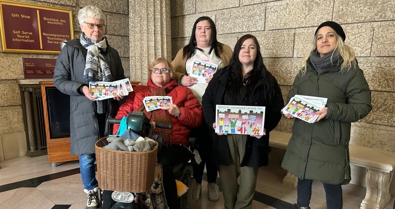 Five people are pictured holding large postcards campaigning for more social housing.