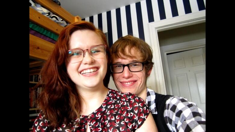 Josh Murphy and Caroline Rex smiling at the camera. They both are wearing glasses. Caroline has red hair. Josh has brown hair.