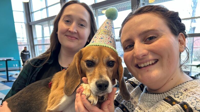 Laura Symes, left, Claire Graham are with Brett the beagle who is wearing a retirement party hat