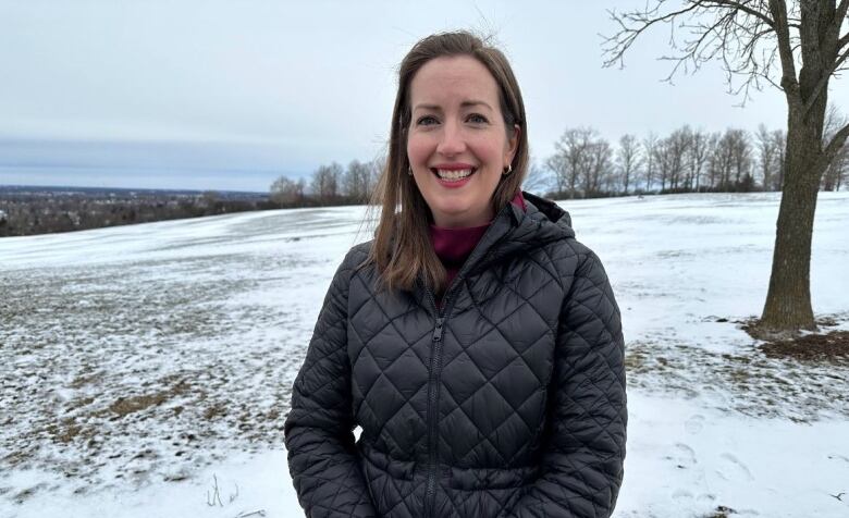 A mayor poses in a park. There's patchy snow on the ground.