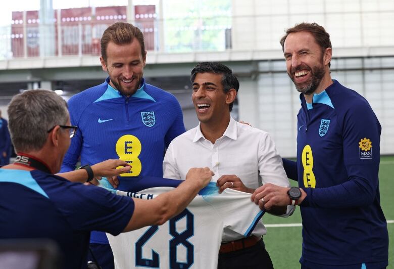 A photographer directs three men how to stand for a photo.