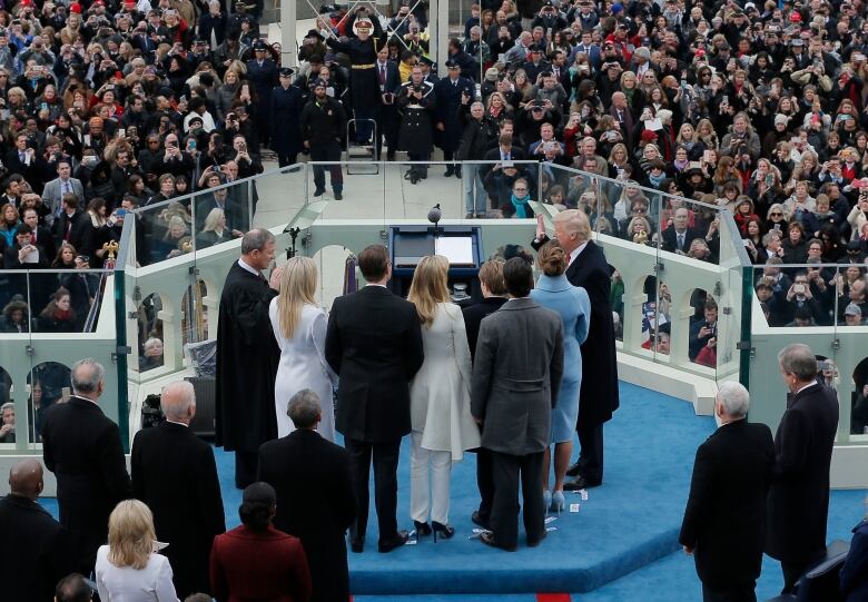 Scene of Trump taking the oath of office in 2017, with hand held aloft as he swears on a bible