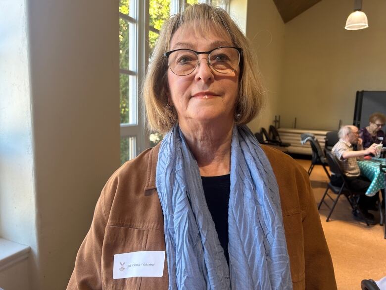 A woman wearing a nametag standing in a hall. 