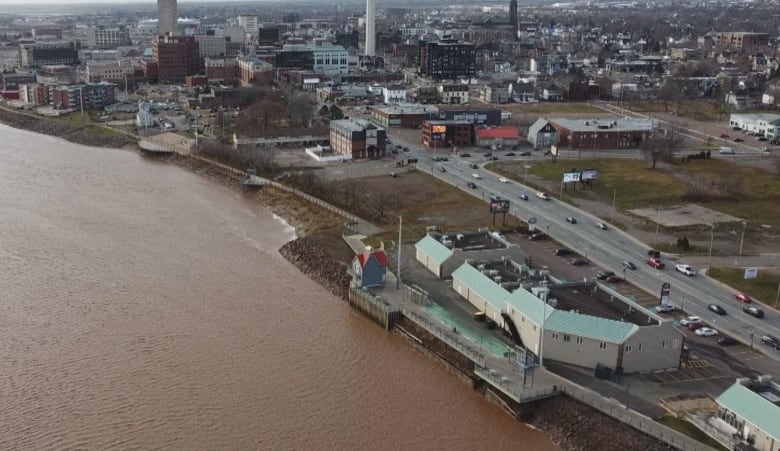 A muddy brown river in the foreground with various buildings in the background. 