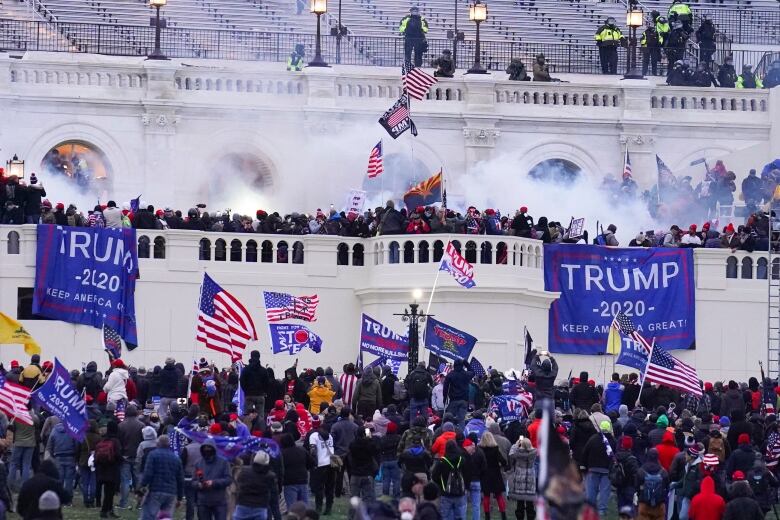 A mob swarms the White House holding banners that say Trump 2020