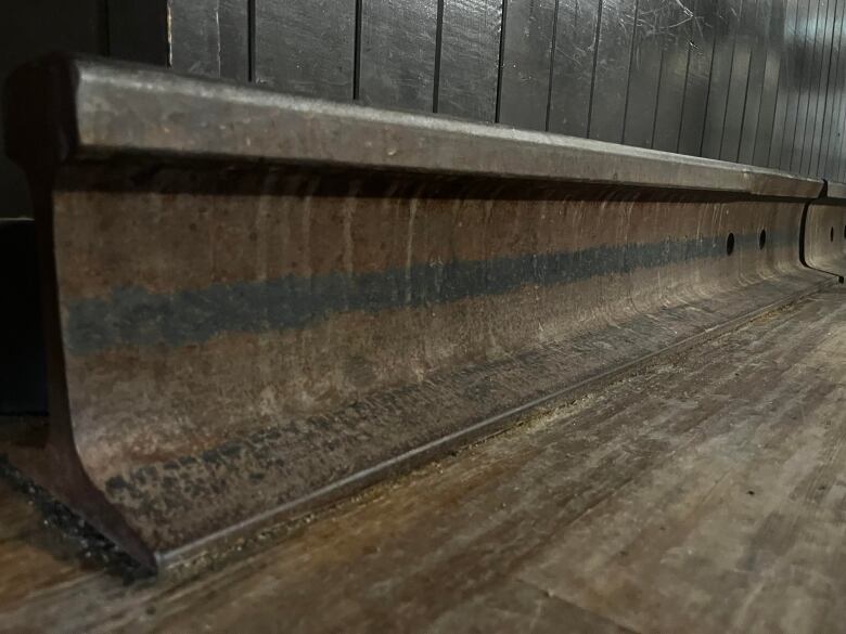 An old train track lies on a wooden floor.