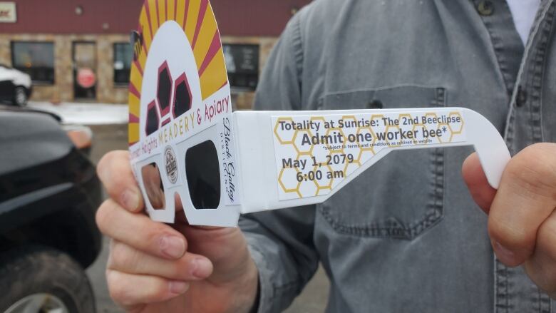 A man holds paper glasses with print on the side that reads 