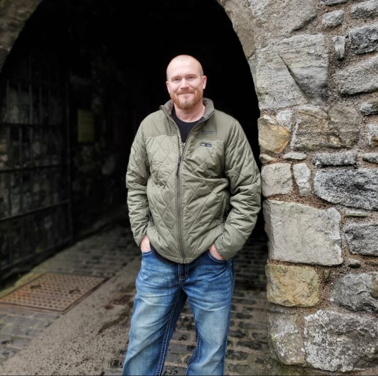 A man in a green coat and jeans.