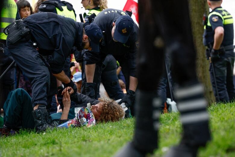 Police officers detain a protesters on the ground.