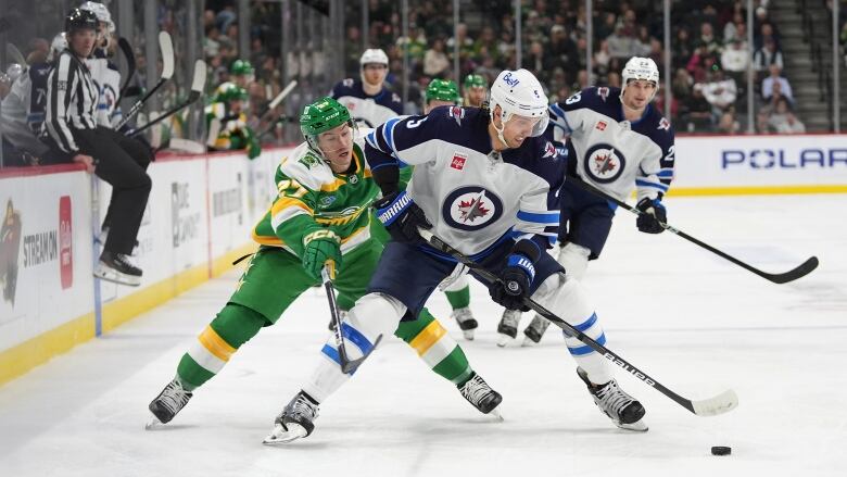 Two hockey players battle for the puck.