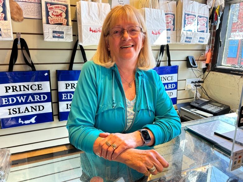 Woman standing behind counter in tourist shop.