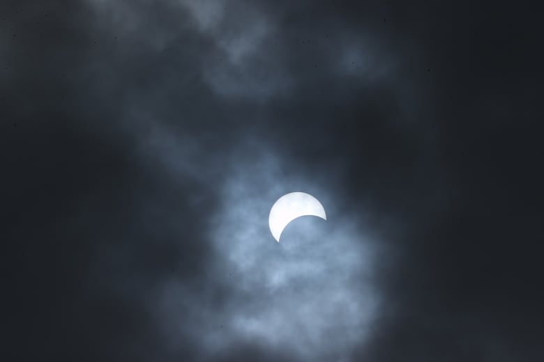 As clouds part, a partial eclipse can be seen beginning over Niagara Falls State Park, N.Y.