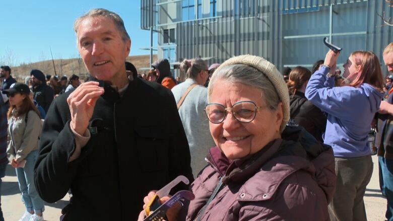 A man and woman in coats smile at the camera. 