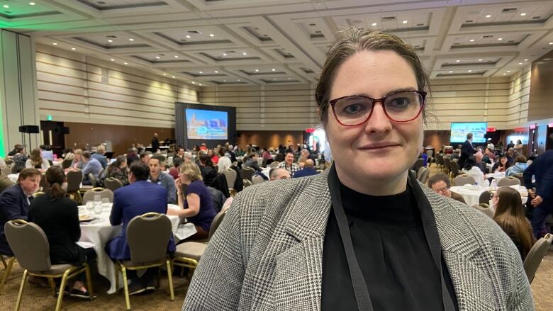 Julia Woodhall-Melnick stands inside a large conference room.