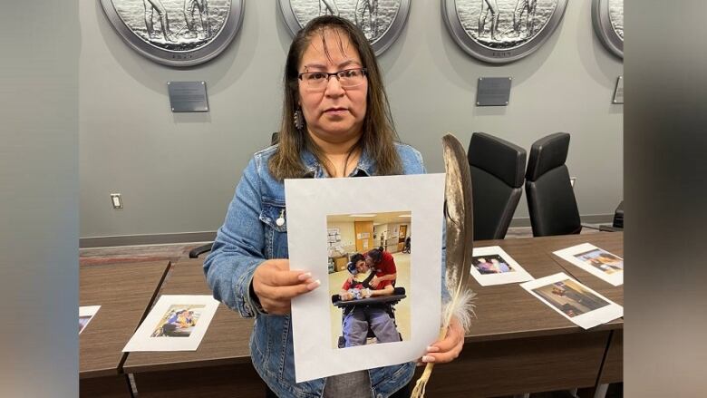 A woman hold a picture of a man in a wheelchair.