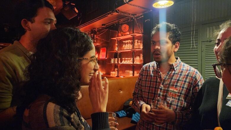 People speaking together inside a bar with flags on their shirts. 