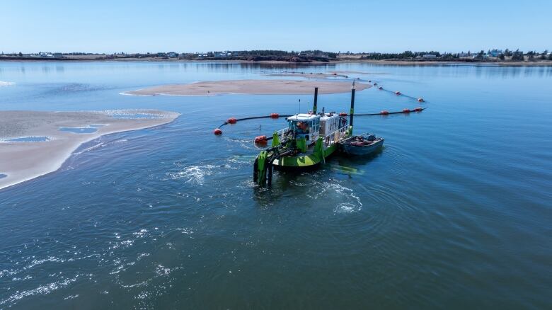 A dredge on a bay with sand banks close by 