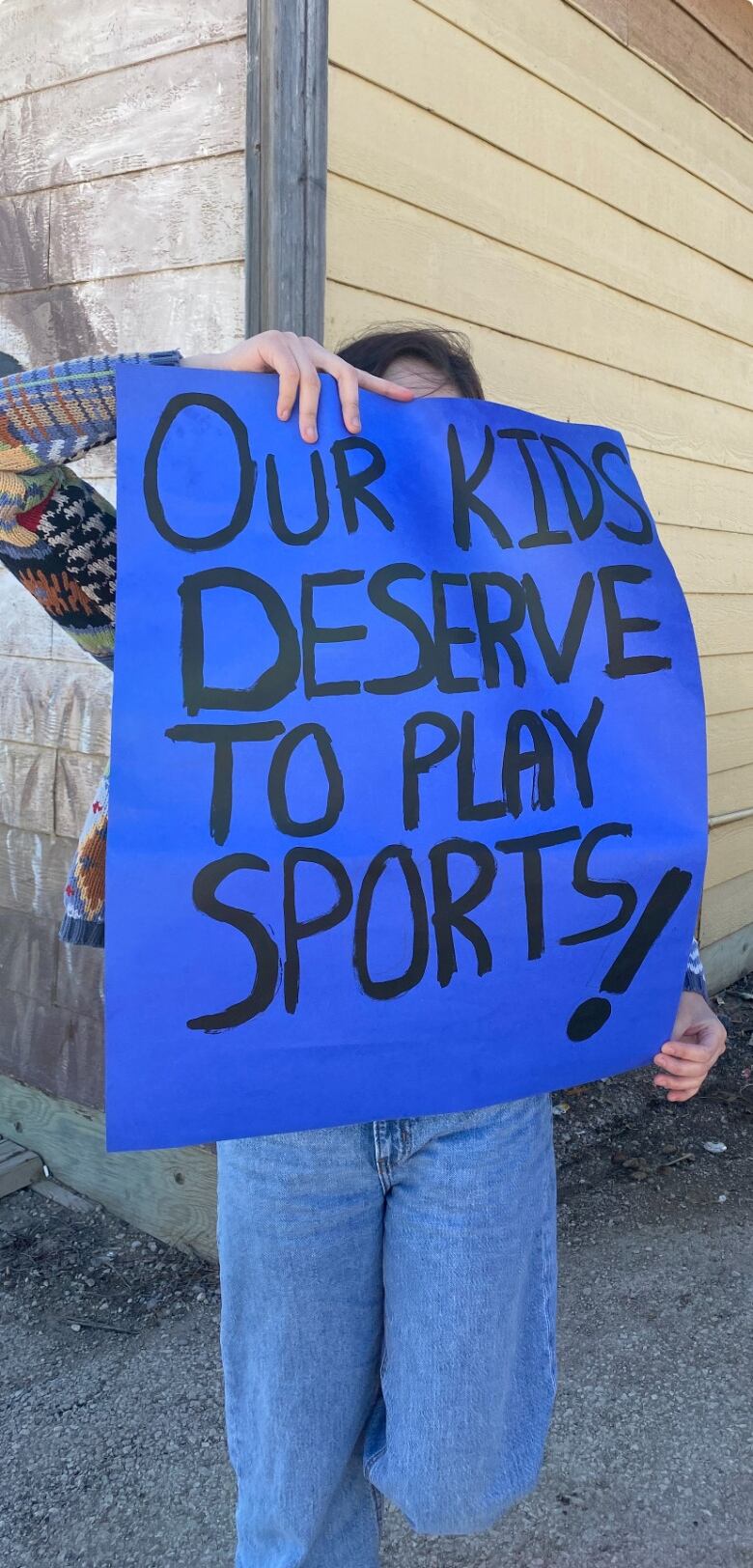 A person holding up a blue sign.