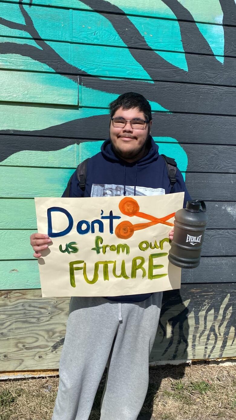 A boy holds a sign that reads, 'dont cut our future.'