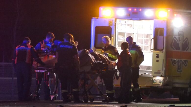 A person on a stretcher is loaded into an ambulance by several paramedics.