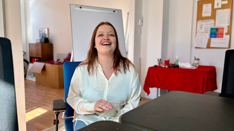 A woman sitting down and laughing. 