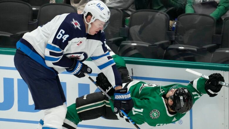 A Winnipeg player knocks a Dallas player backwards along the boards.