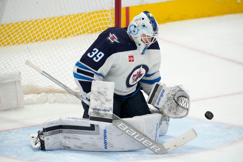 A goaltender stops a puck while in the butterfly position.