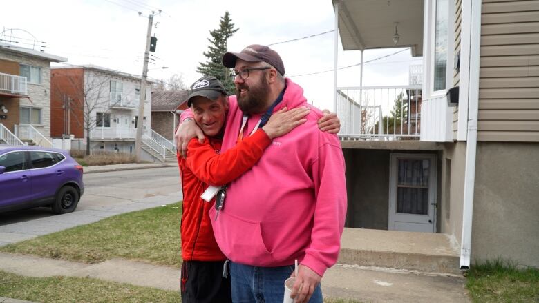 two men hugging in a driveway