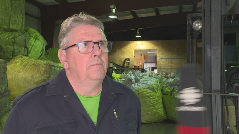 A man with glasses standing in a warehouse.