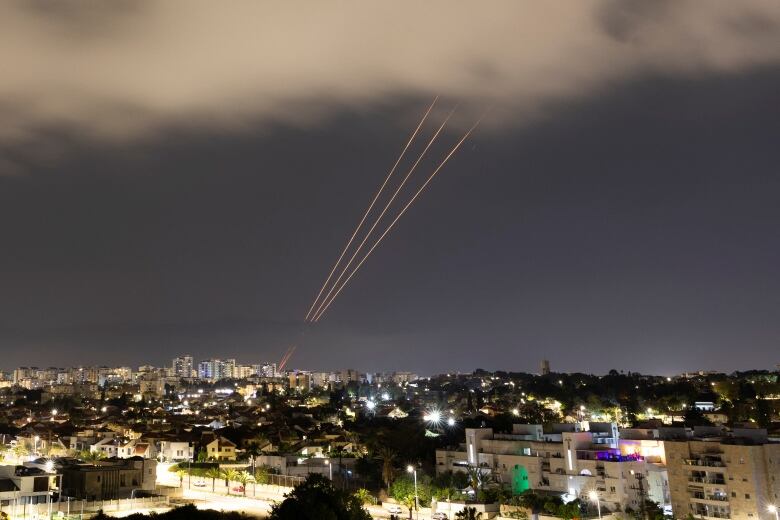 Streams of light are seen above a city.