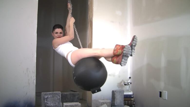 A woman on a wrecking ball wearing a tank top is pictured.