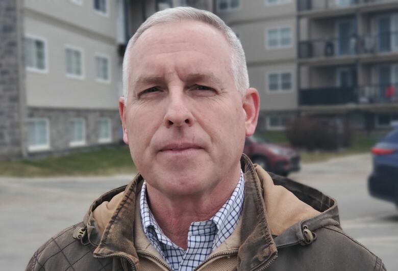 Willy Scholten stands outside in front of an apartment building.