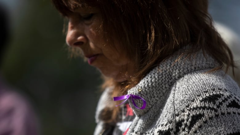 A mother wears a purple ribbon during a Moms Stop The Harm memorial on the seventh anniversary of the opioid public health emergency in Vancouver on April 14, 2023.