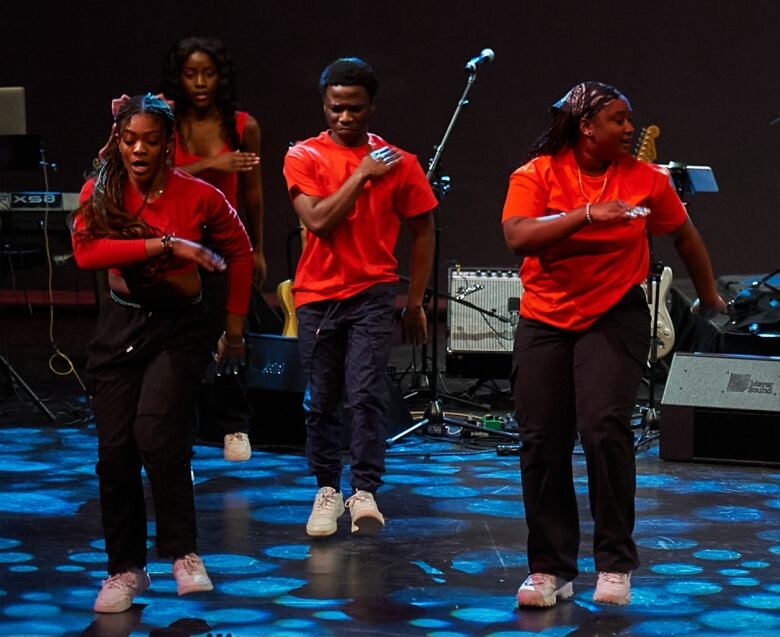 Three members of an Afrobeats dance group are captured mid-step during a performance. 