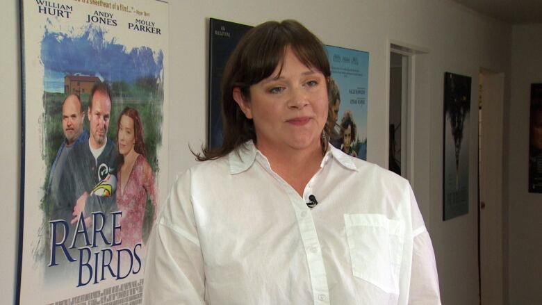 Woman in a white shirt standing in front of posters. 