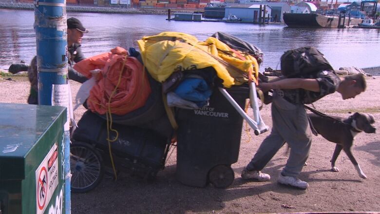 two men move a cart and garbage can 