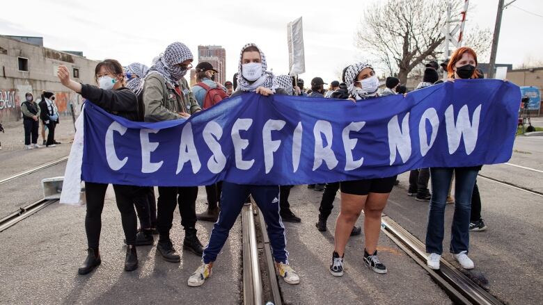 Protesters block a rail line in Toronto during a rally organized by World Beyond War on April 16, 2024.