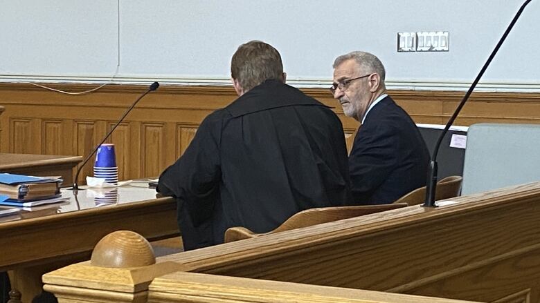 A man speaks with his lawyer in court.