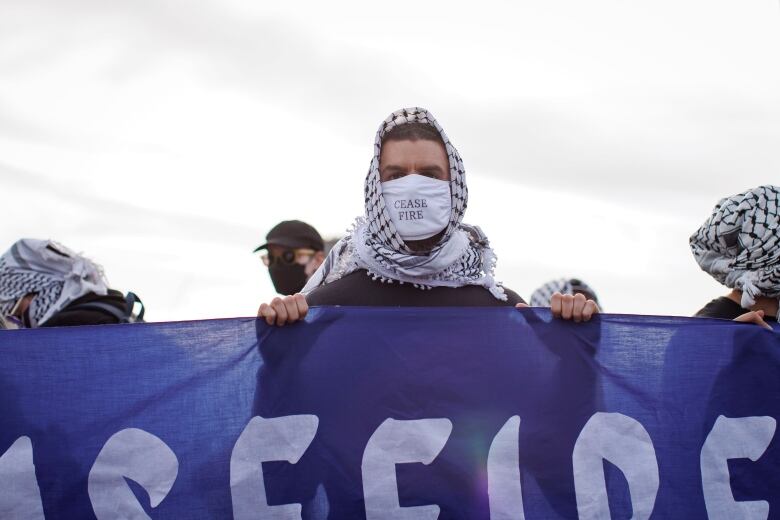 Protesters who blocked a rail line in Toronto on Tuesday wear keffiyehs. The protest was organized by World Beyond War on April 16, 2024.