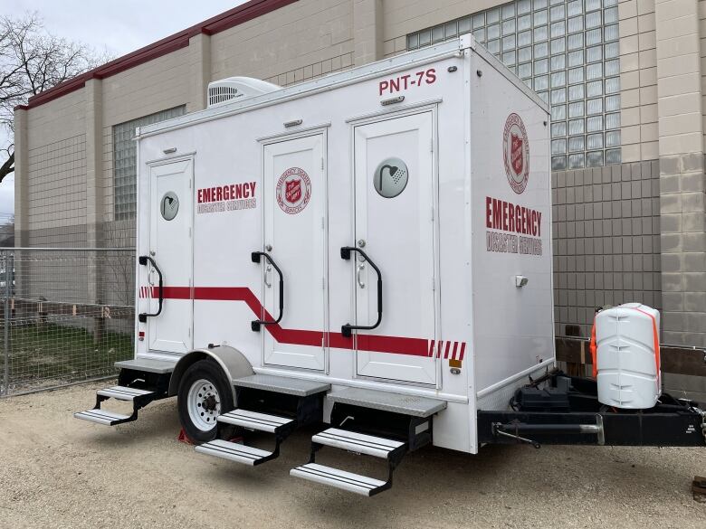 A white trailer with Salvation Army logos and icons representing showers on the doors.