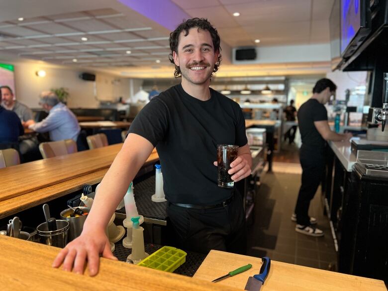 A man stands with a drink in his hand. 