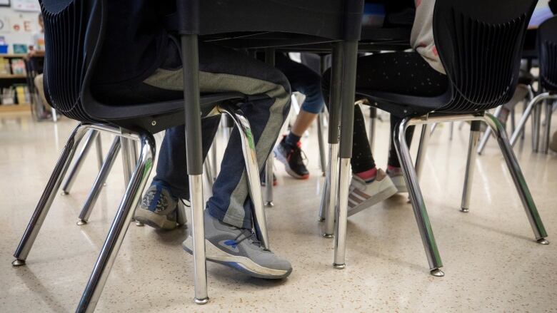 The legs of children underneath school desks