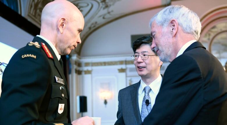 Three men shake hands and chat