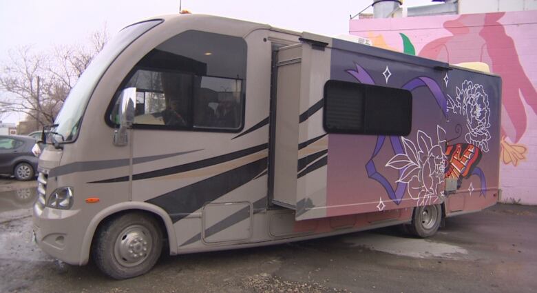 A large recreation vehicle is painted with flowers and butterflies on the side.