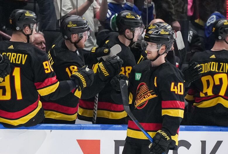 A hockey player skates past the bench and high-fives his teammates.