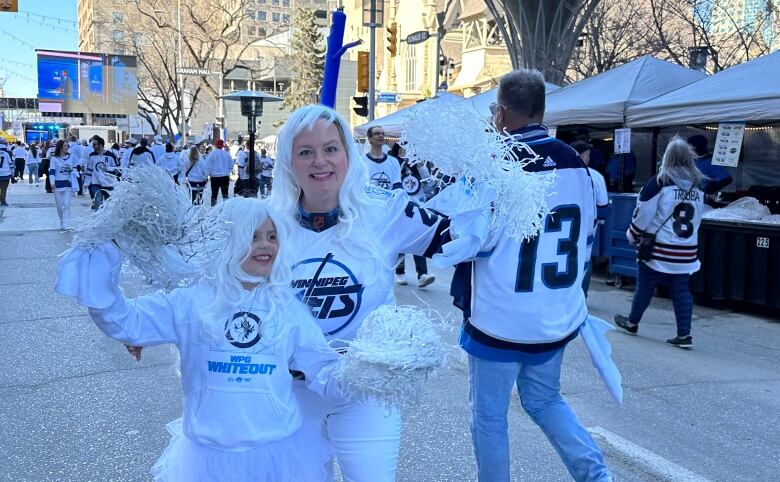 A woman and a girl dressed up in white cheerleading outfits.