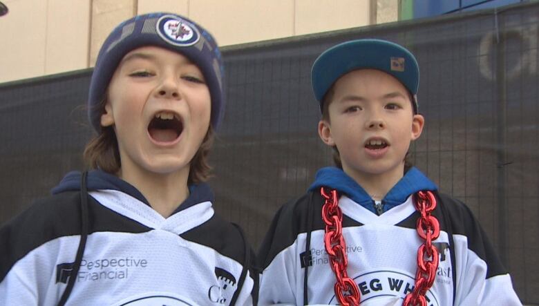 Two kids wearing hockey jerseys.