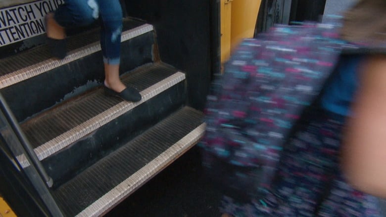 Two students walking off of a bus