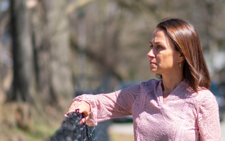 A woman leans on a fence outside in spring.