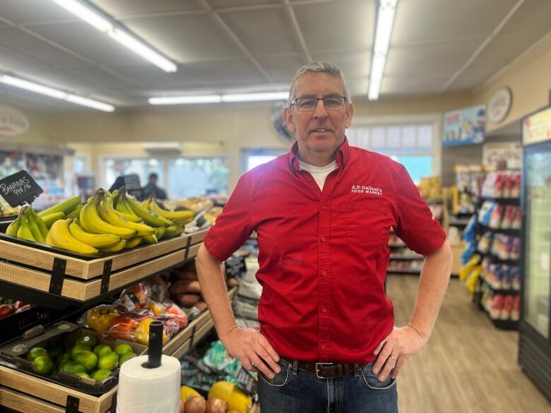 Man standing beside bananas in grocery store.